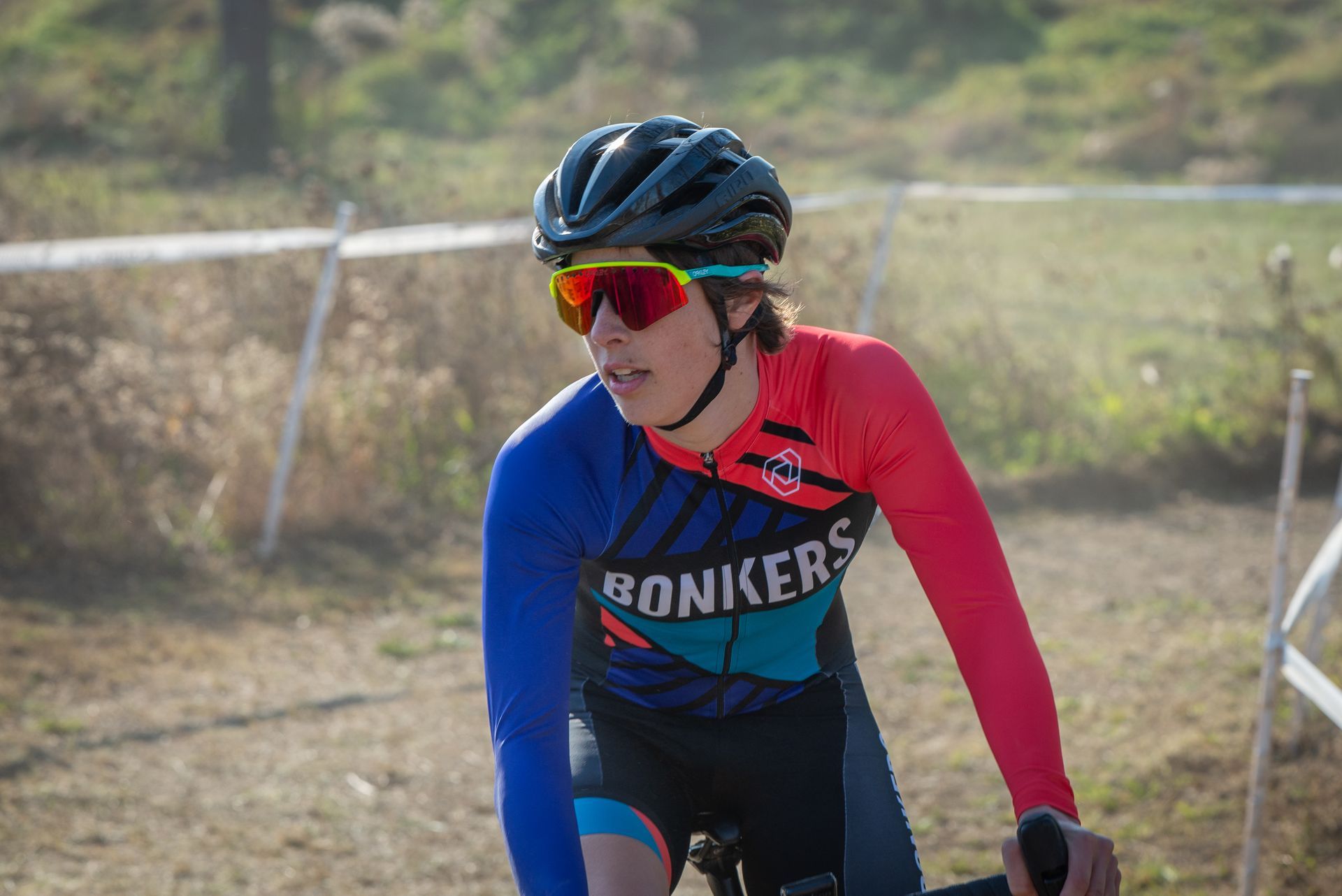 A person wearing a helmet and sunglasses is riding a bike on a dirt road.