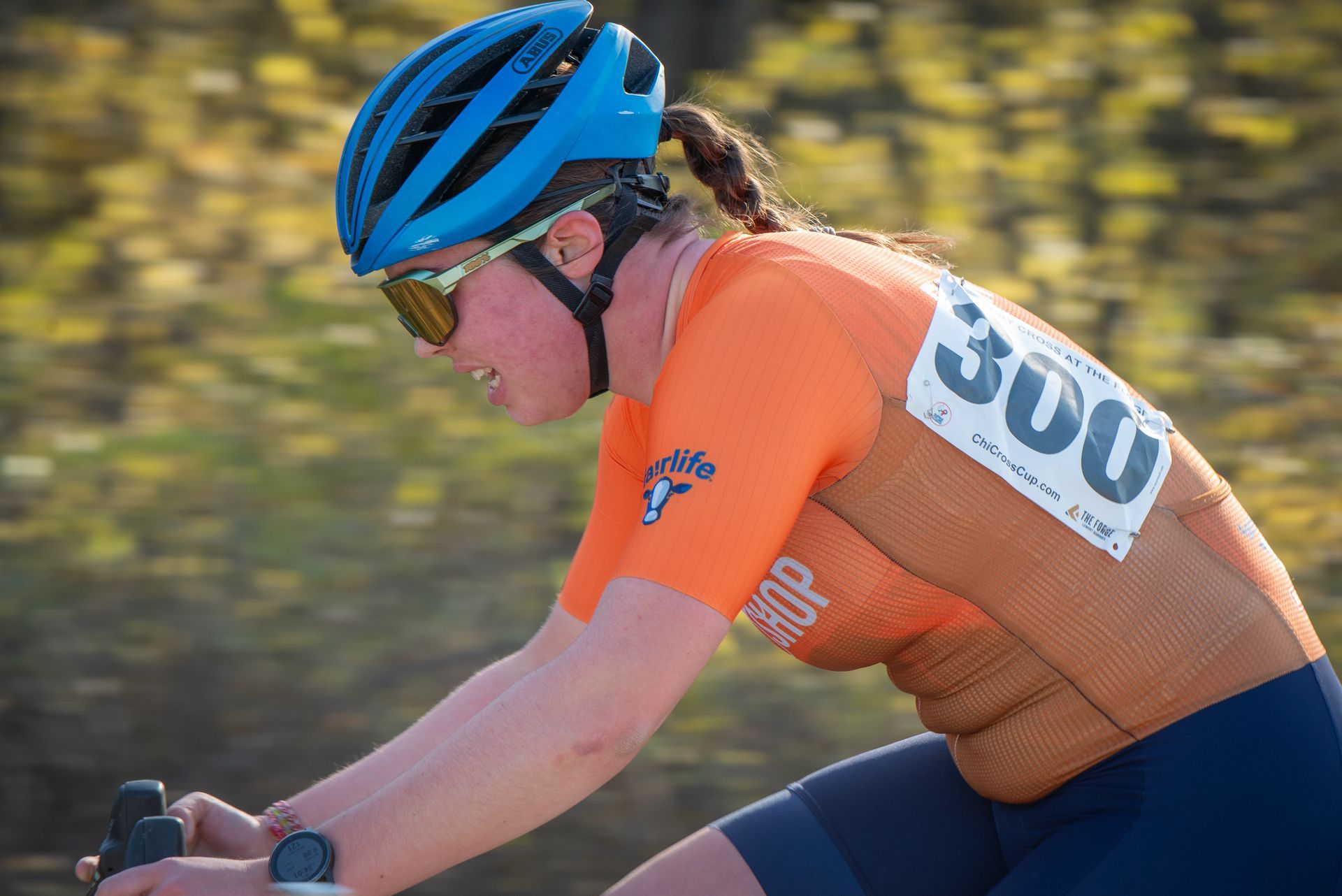A woman wearing a helmet and sunglasses is riding a bike.