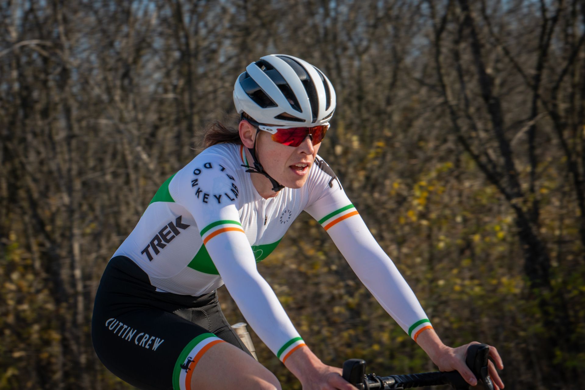 A woman wearing a helmet and sunglasses is riding a bike.
