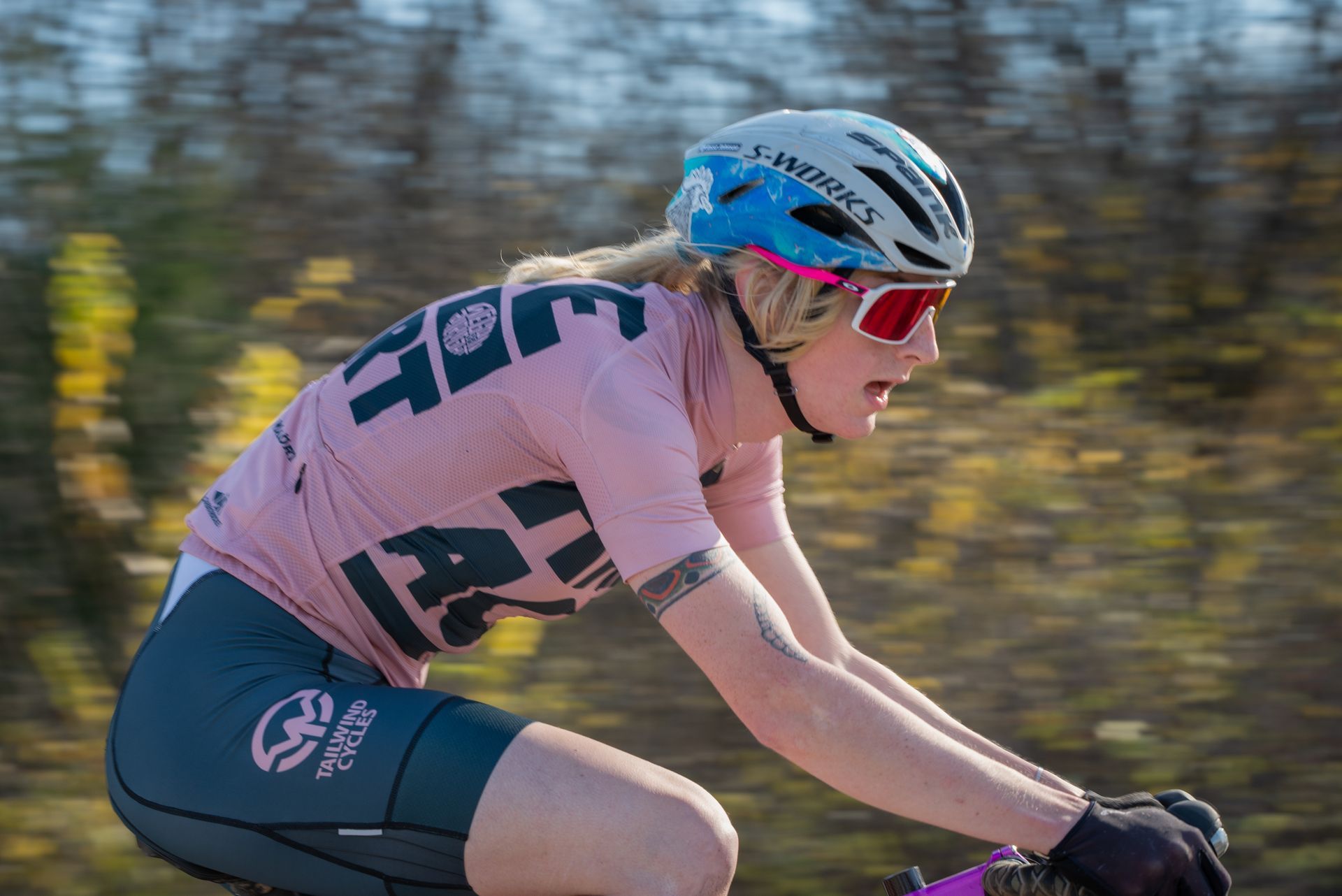 A woman wearing a helmet and sunglasses is riding a bike.