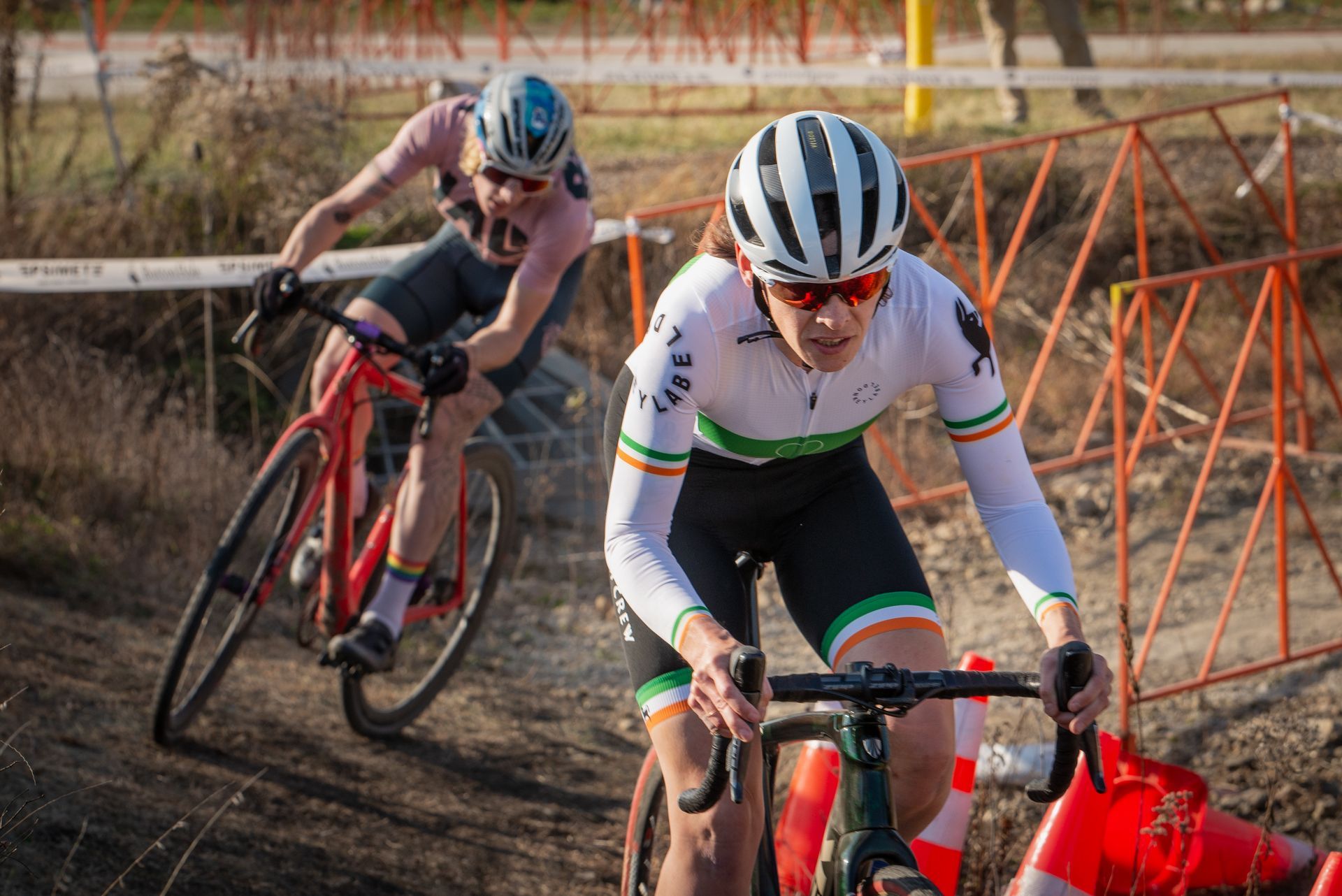 Two people are riding bicycles on a dirt road.