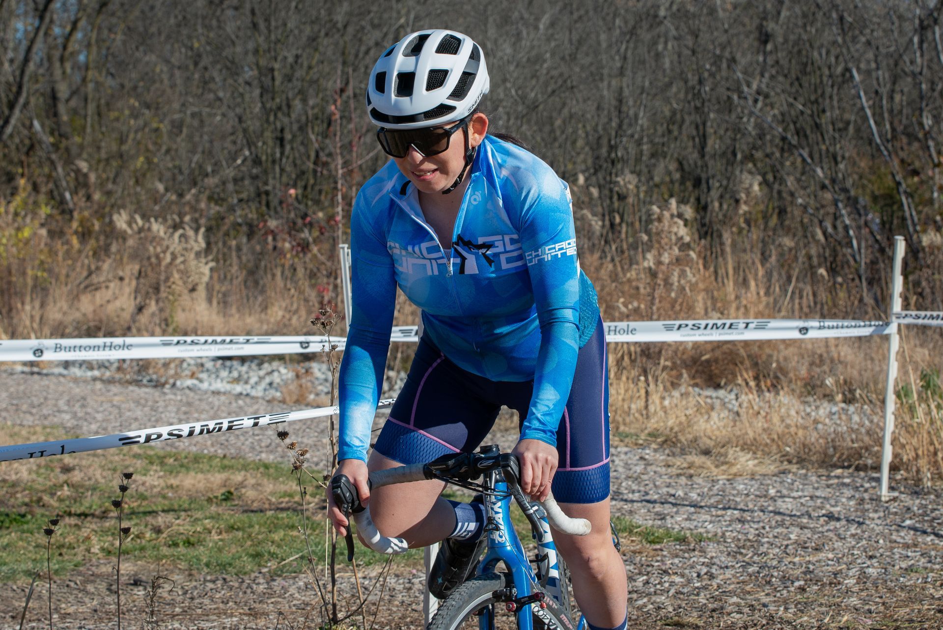 A woman wearing a helmet and sunglasses is riding a bike.