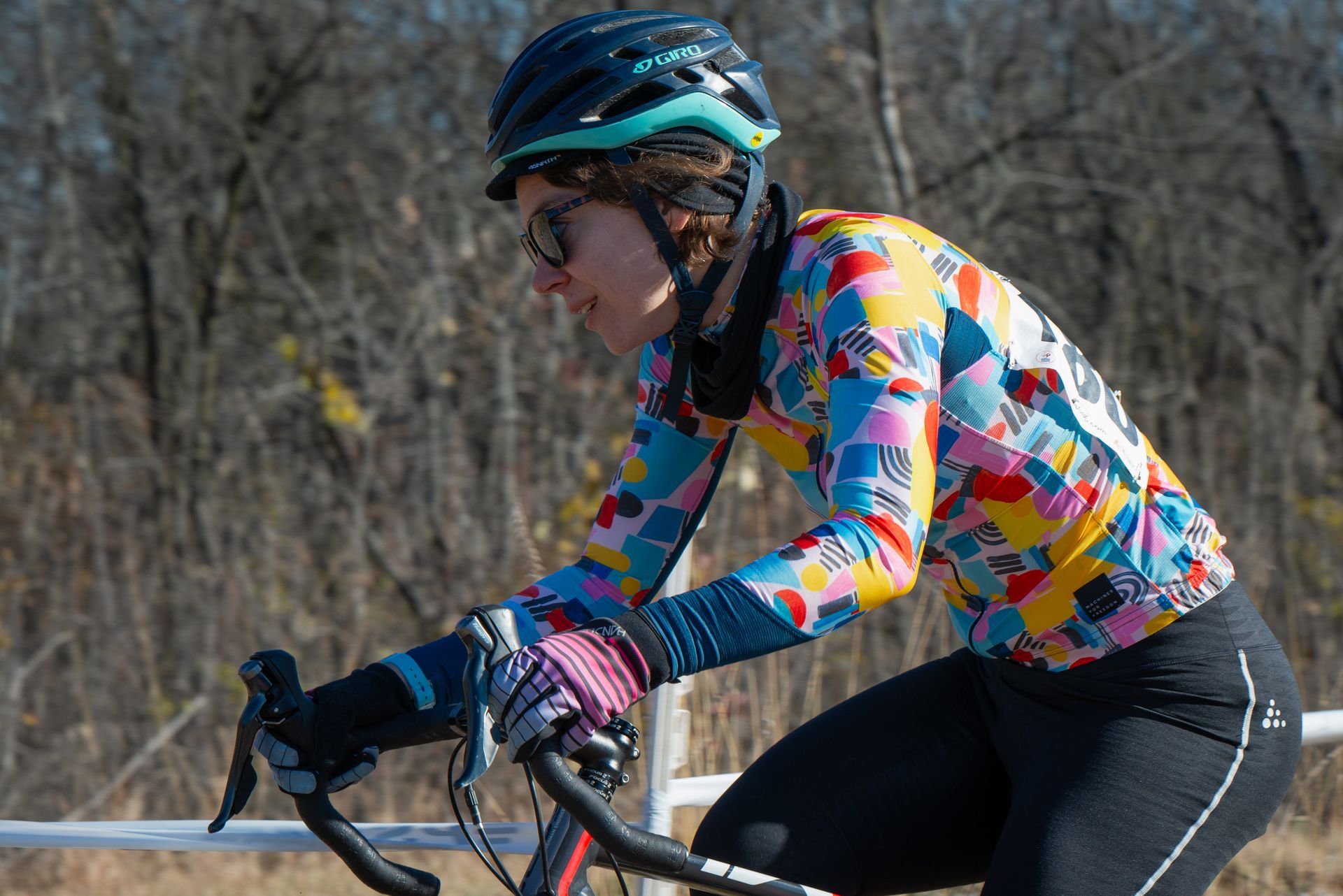 A woman wearing a helmet and a colorful shirt is riding a bike.