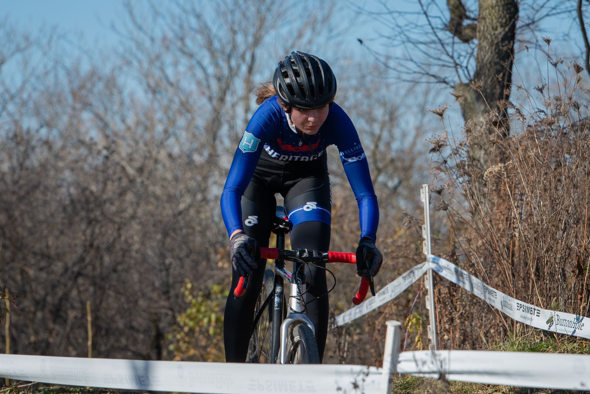 A person is riding a bike on a road next to a fence.
