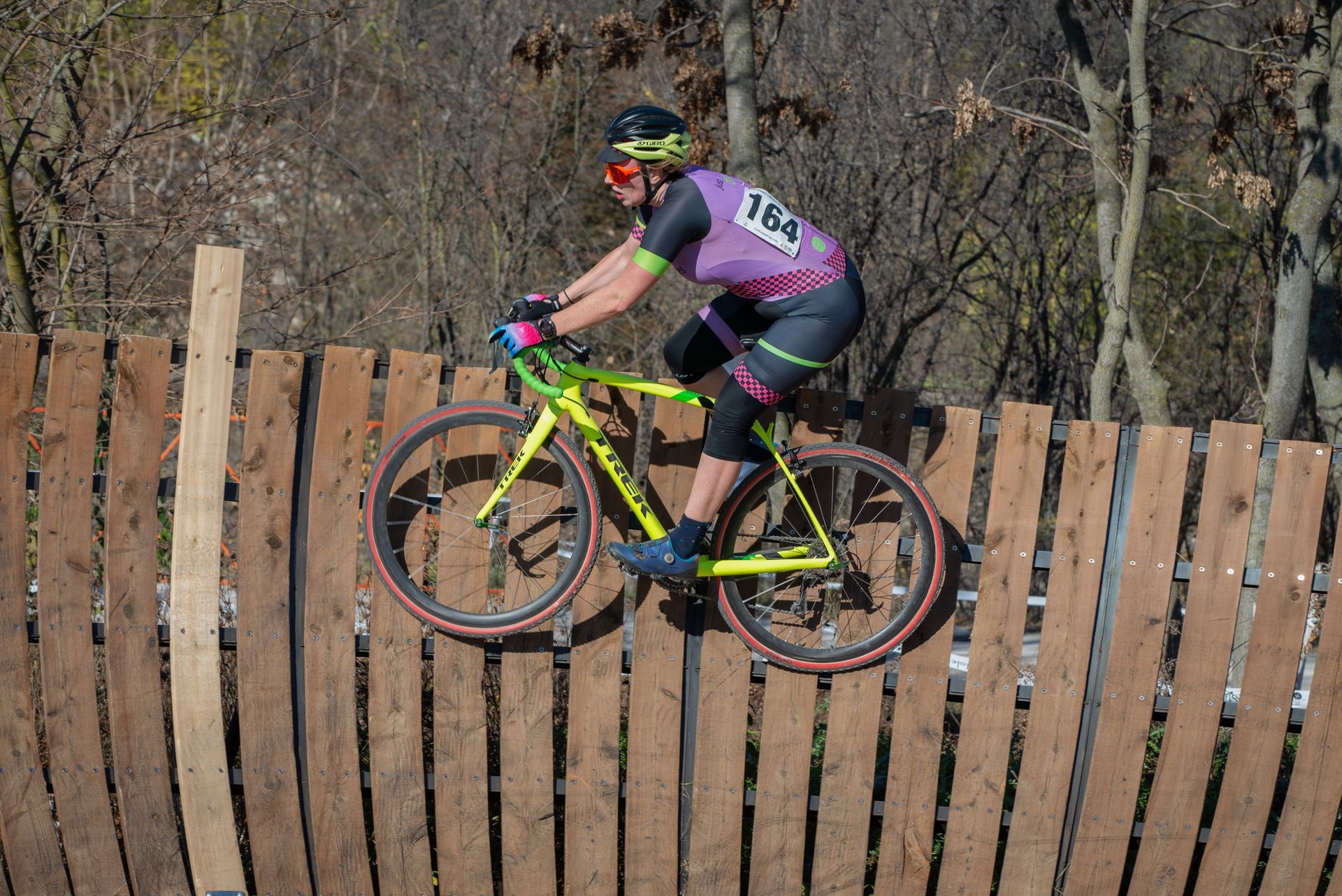 A person is riding a bike over a wooden fence.