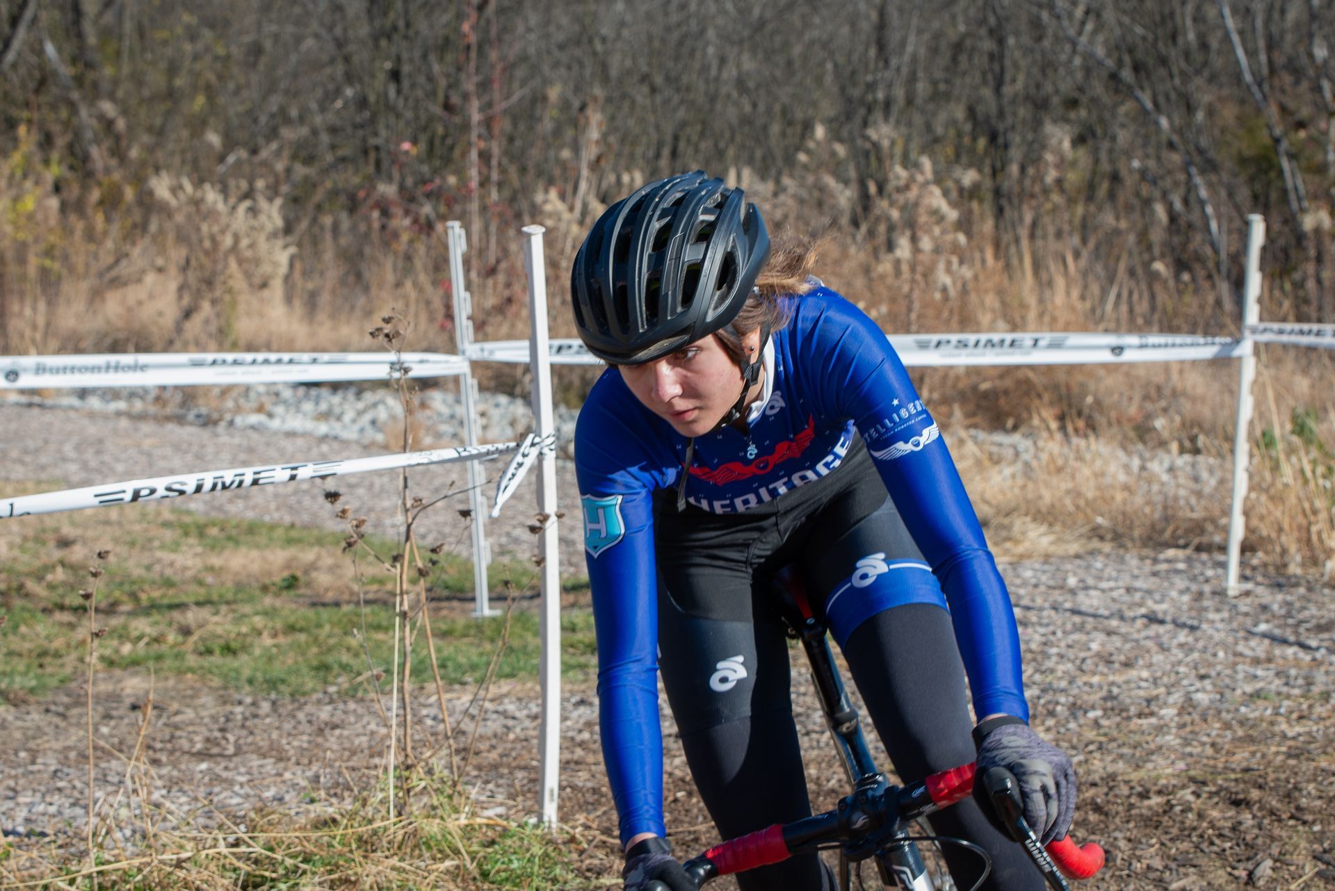 A woman wearing a helmet is riding a bike on a dirt road.