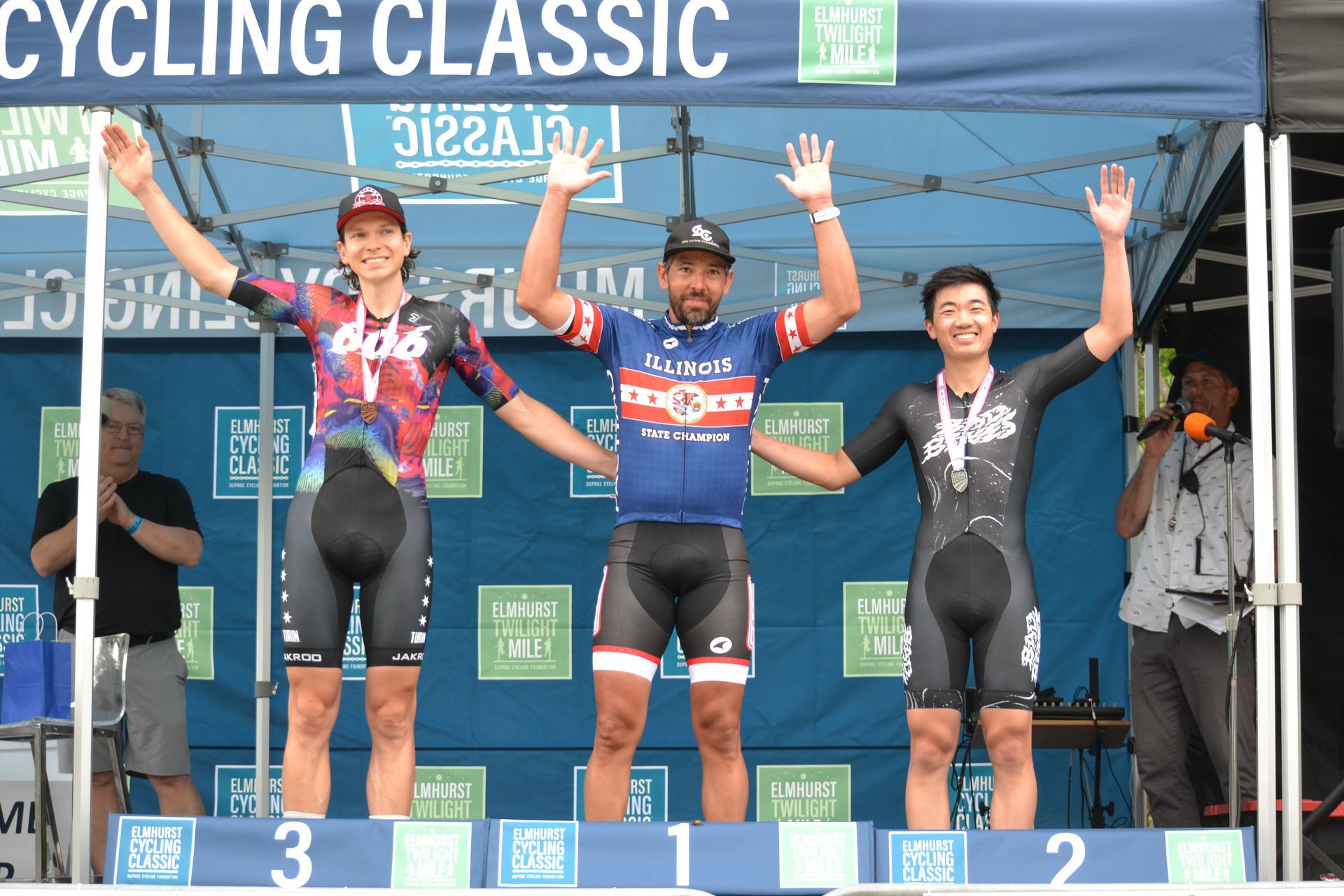 Three cyclists are standing on a podium at a cycling classic