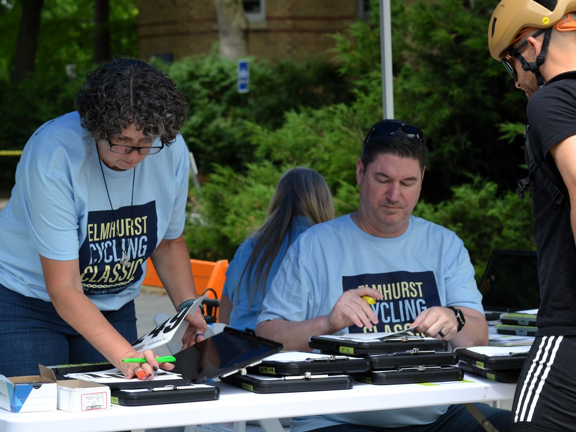 A man wearing a helmet sits at a table with a woman wearing a shirt that says elmhurst cycling