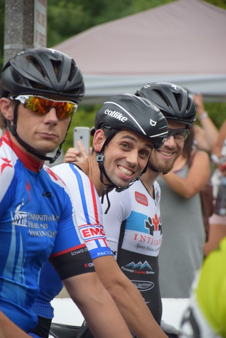A group of cyclists wearing helmets and sunglasses are posing for a picture.