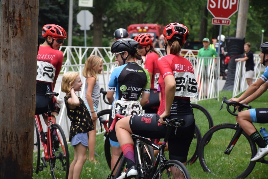 A group of people riding bicycles in a park with a stop sign in the background.
