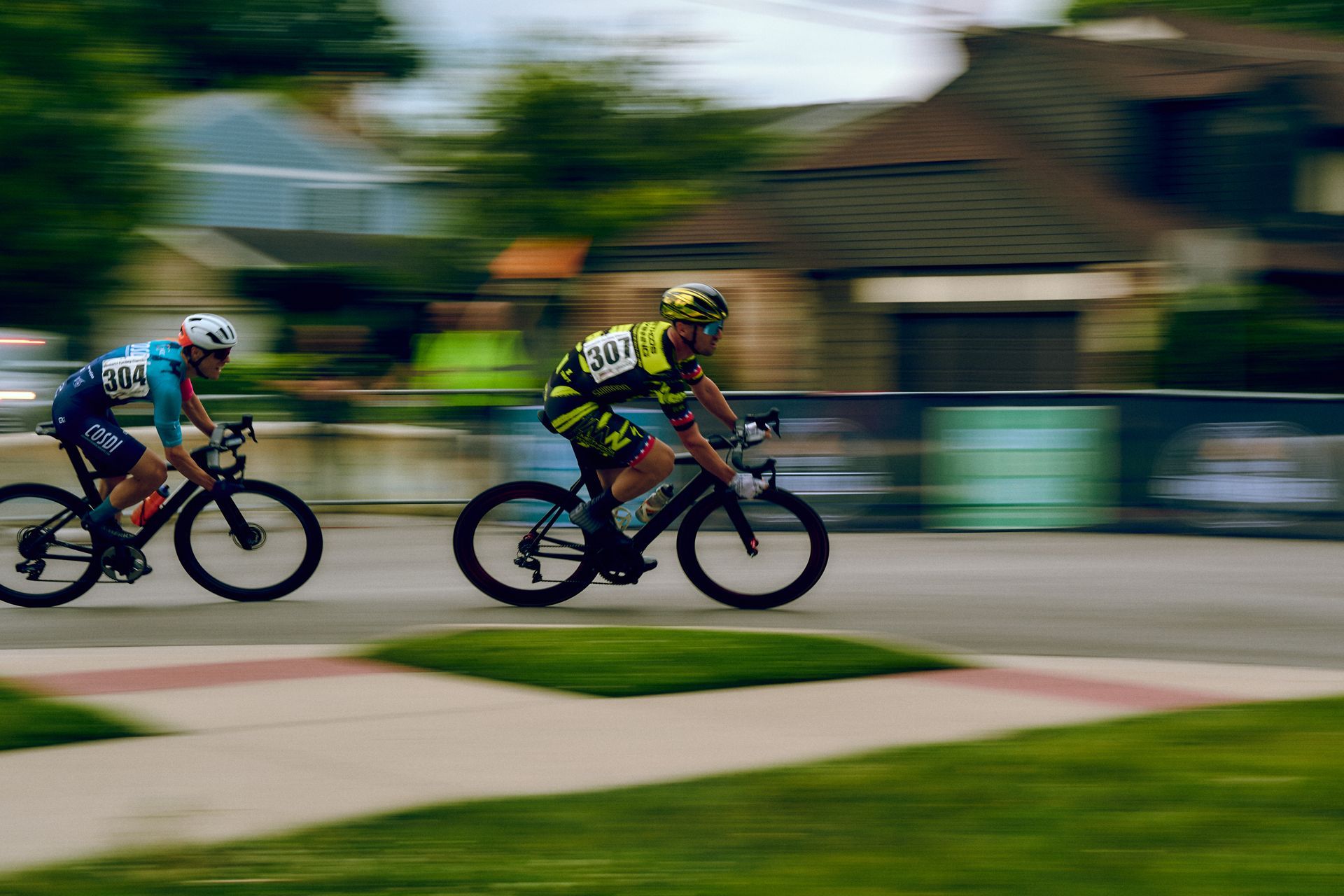 Two people are riding bicycles down a street.