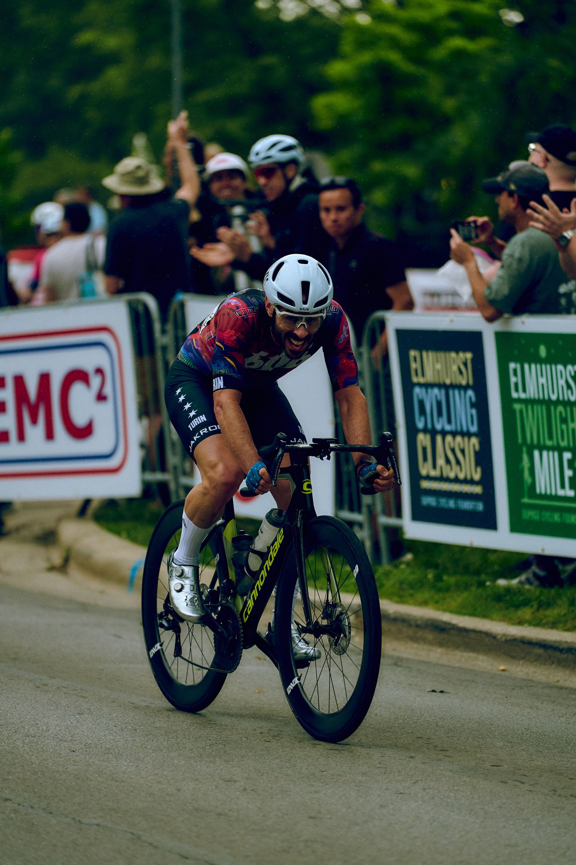 A man is riding a bike in front of a sign that says emc2