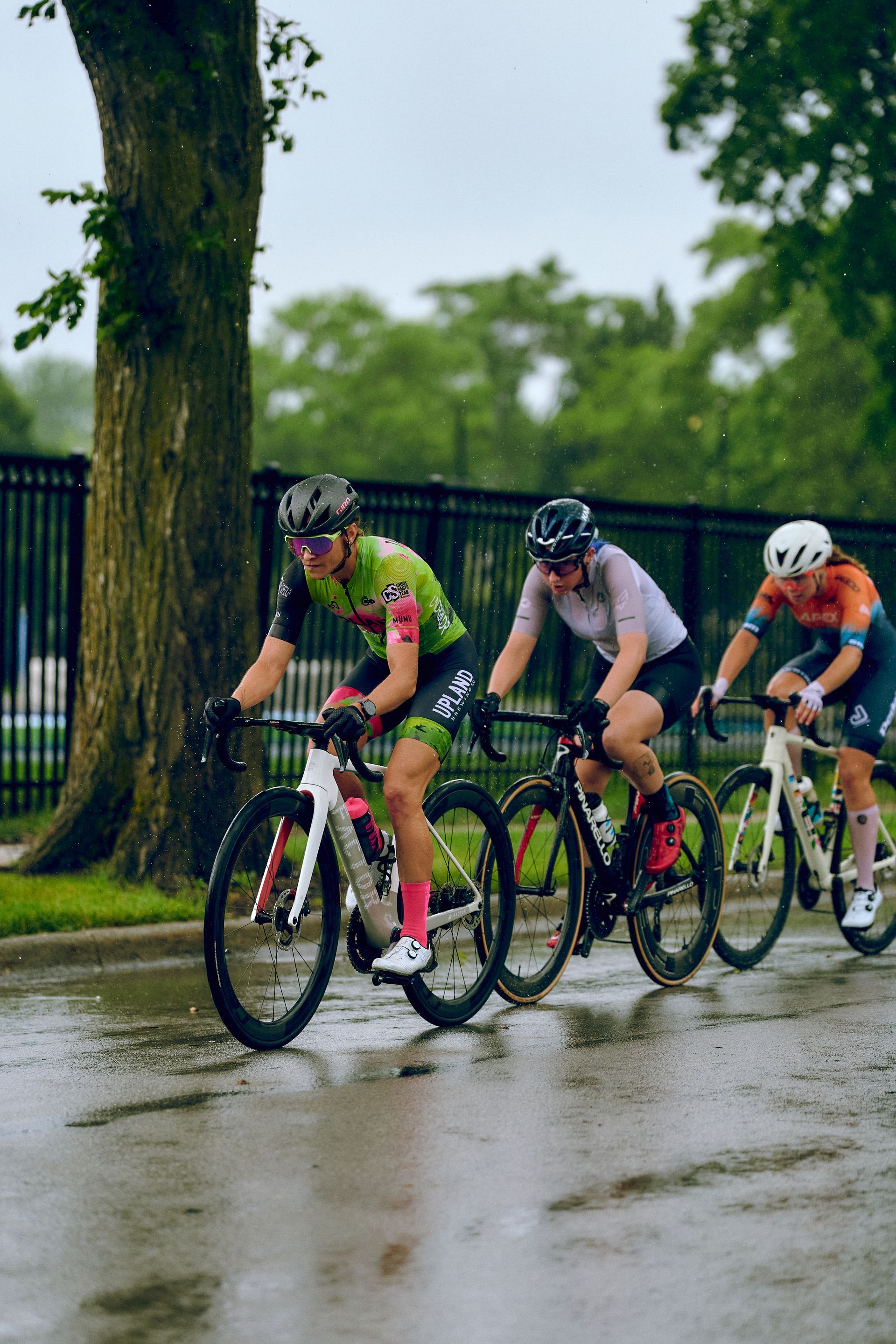 A group of people are riding bicycles down a wet street.