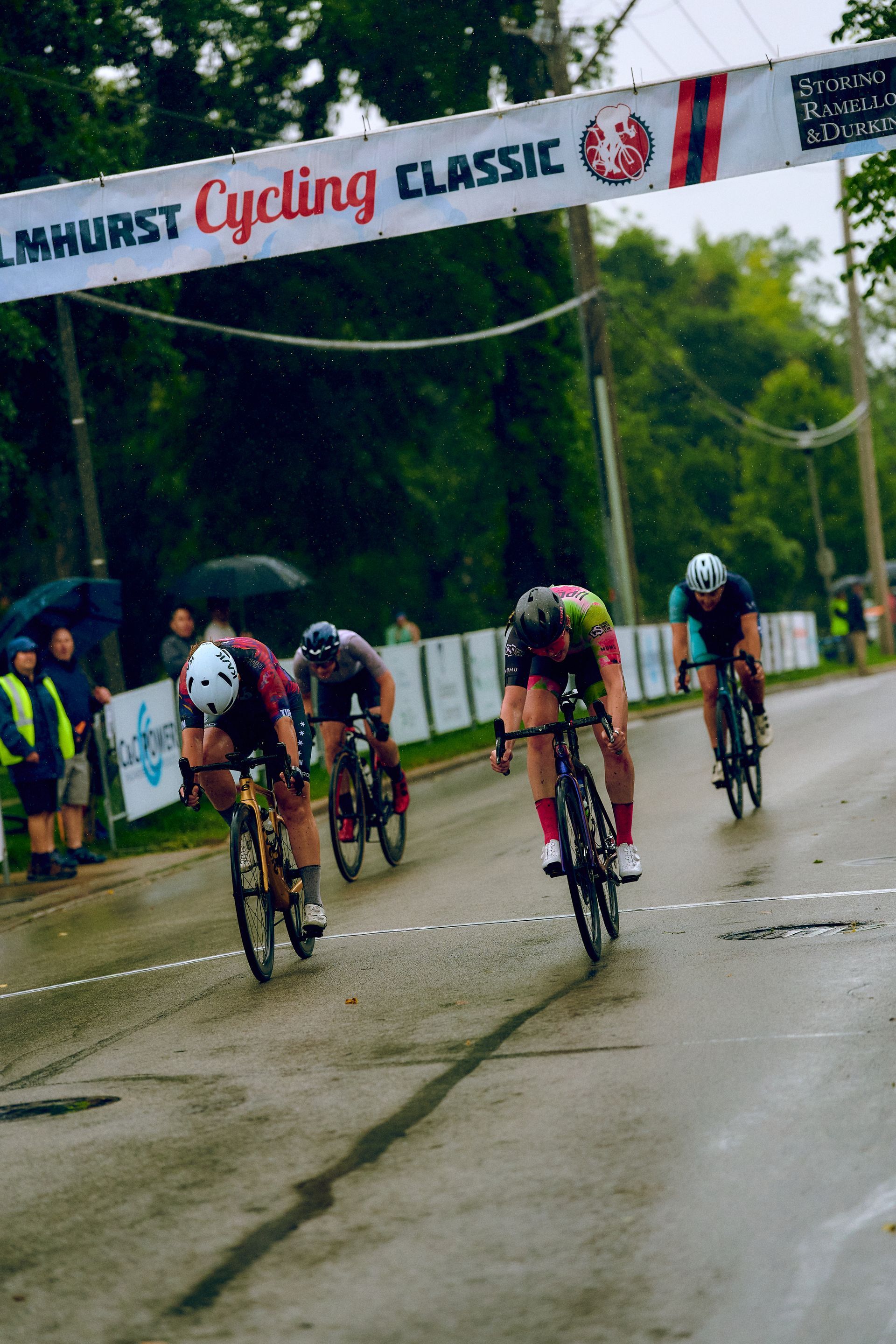 A group of cyclists are racing under a banner that says limhurst cycling classic