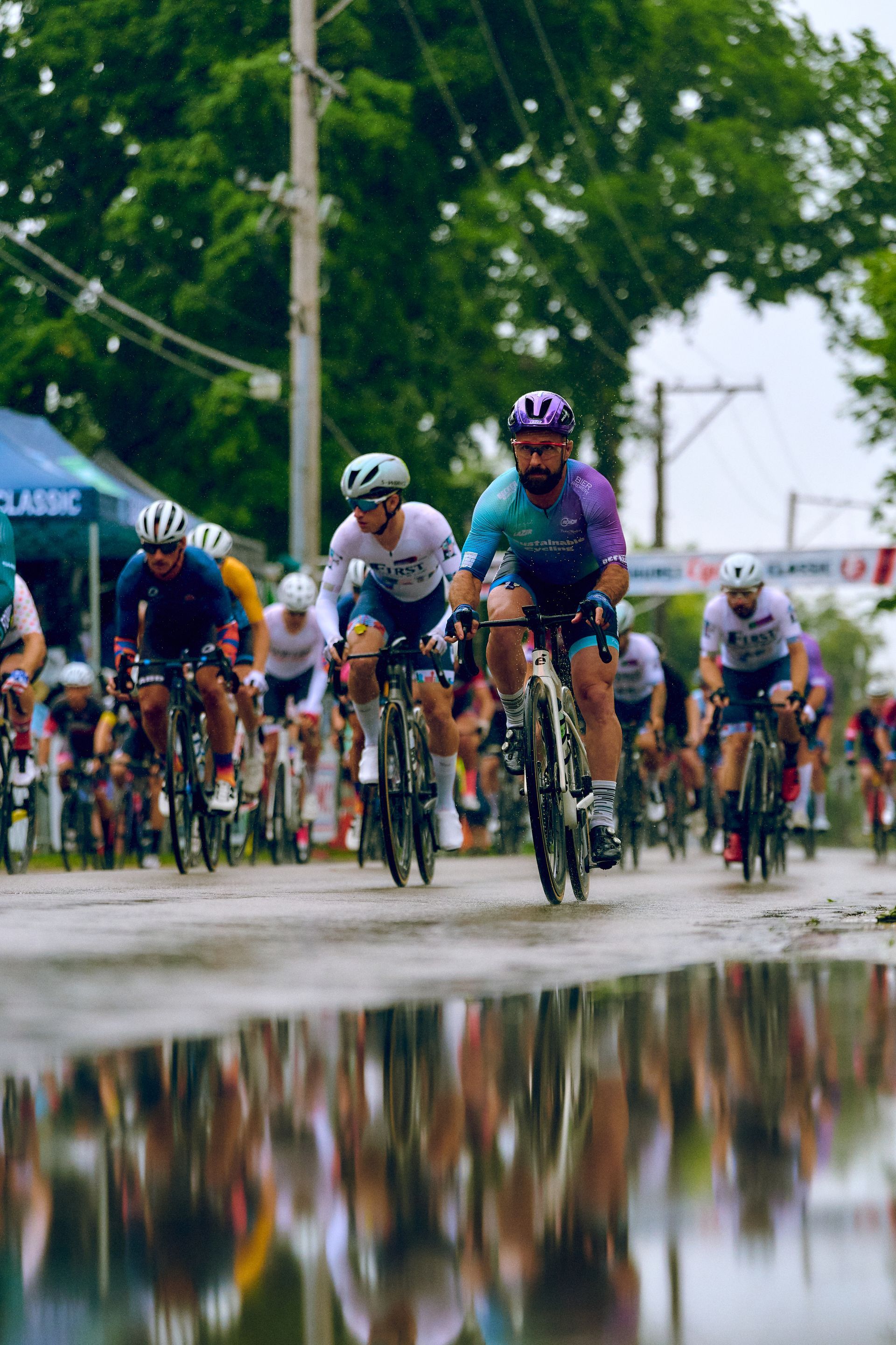 A group of people are riding bicycles down a wet street.