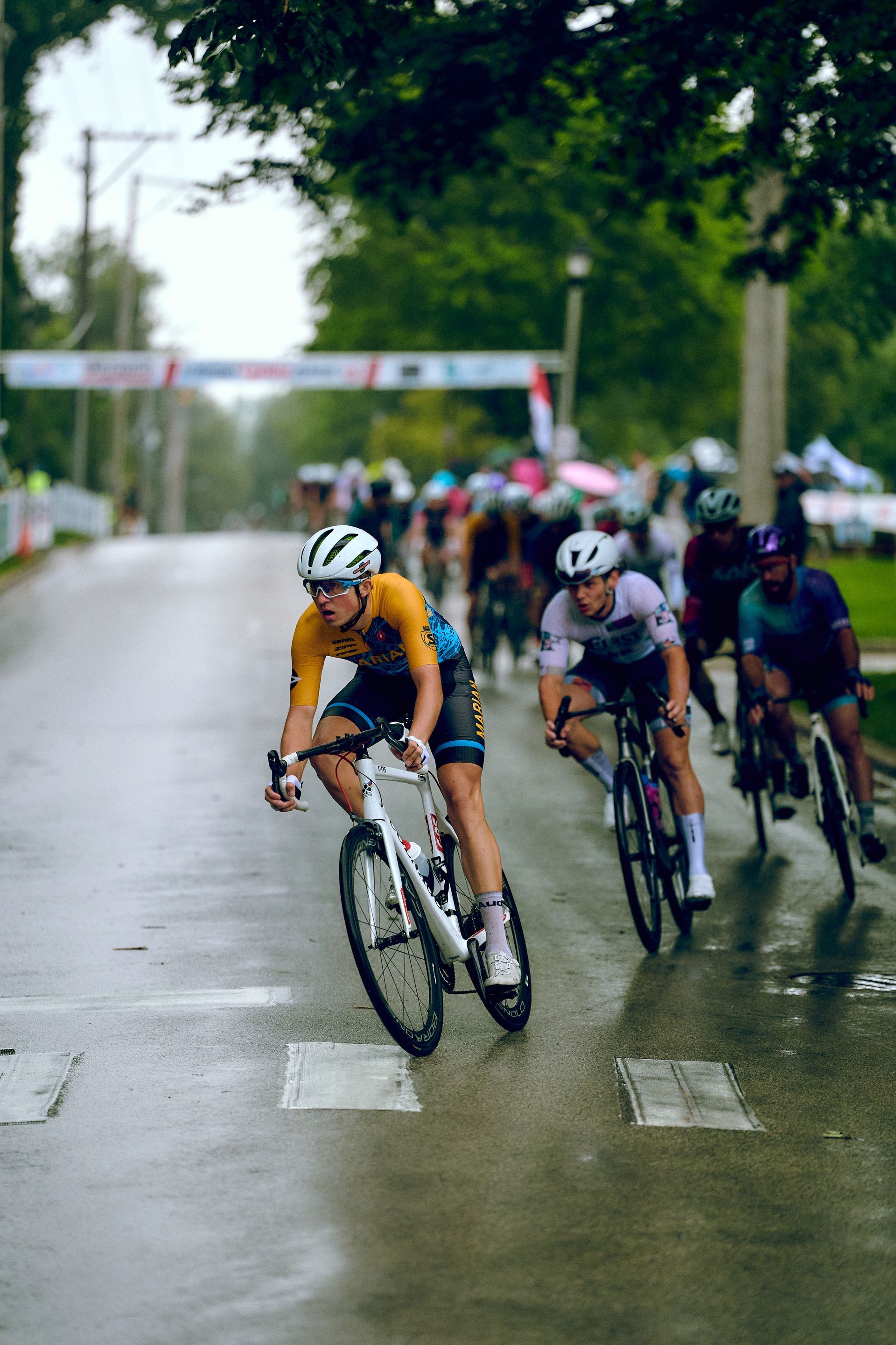 A group of people are riding bicycles down a wet road.