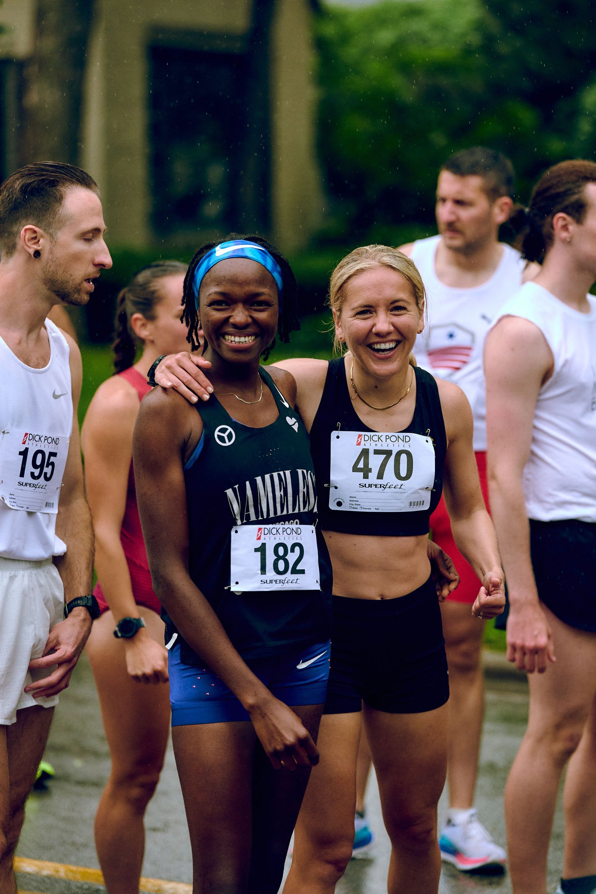 A group of runners are posing for a picture and one of them has the number 470 on her shirt