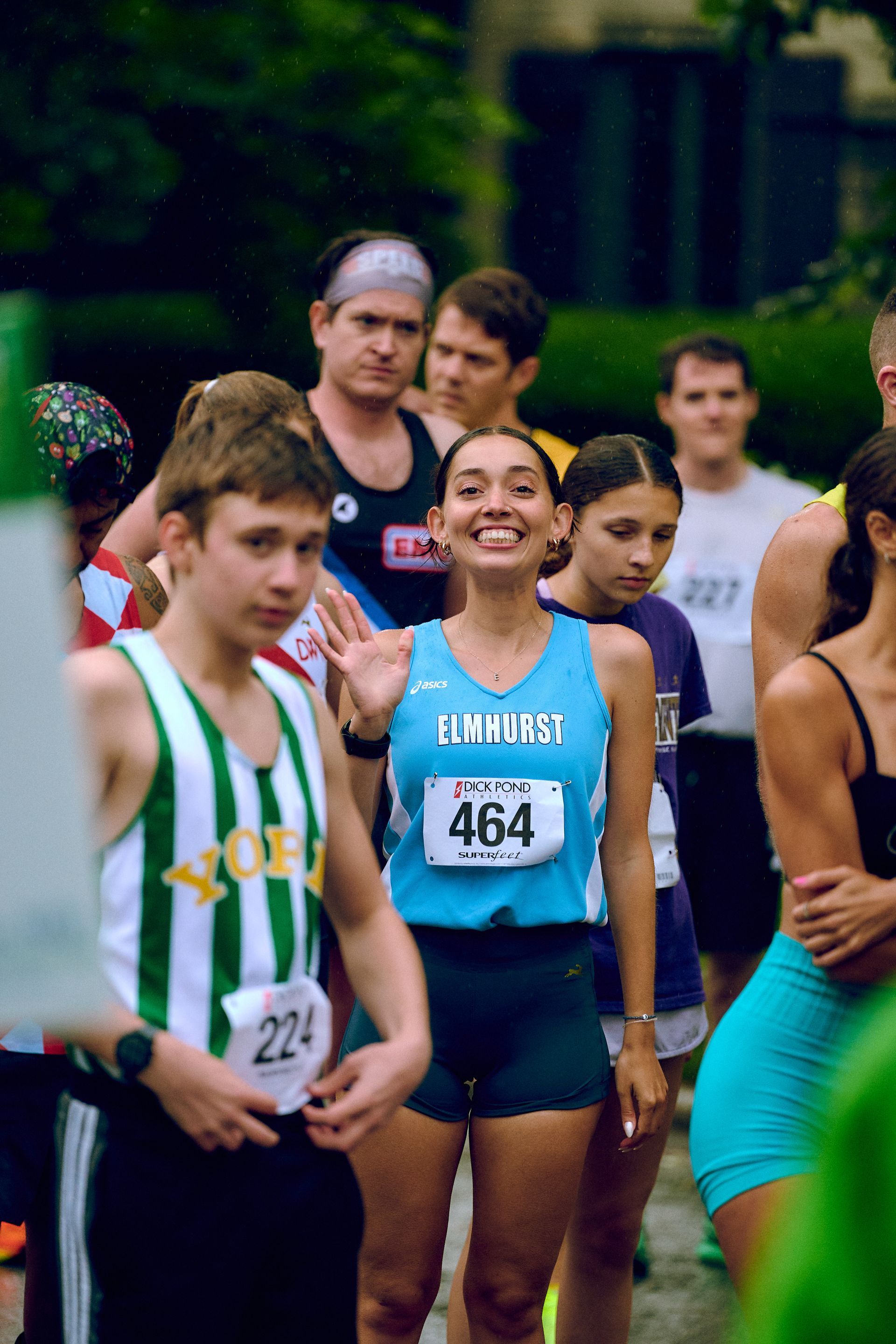 A group of people are standing in a line with a woman wearing a blue tank top with the number 454 on it.