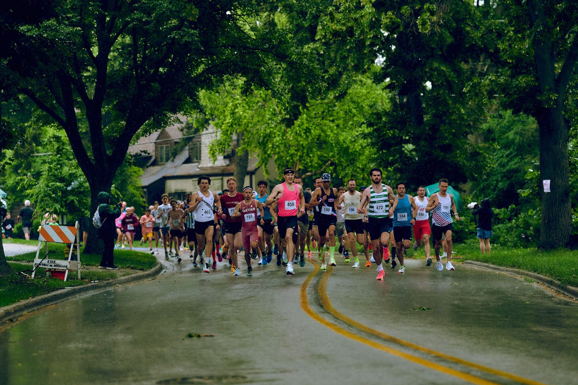 A group of people are running down a road with trees in the background