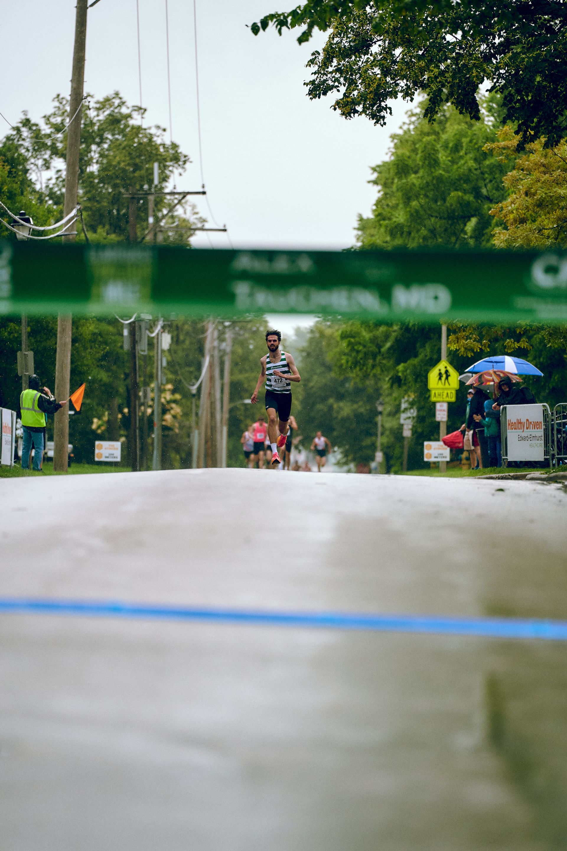 A man is running a marathon on a wet street.