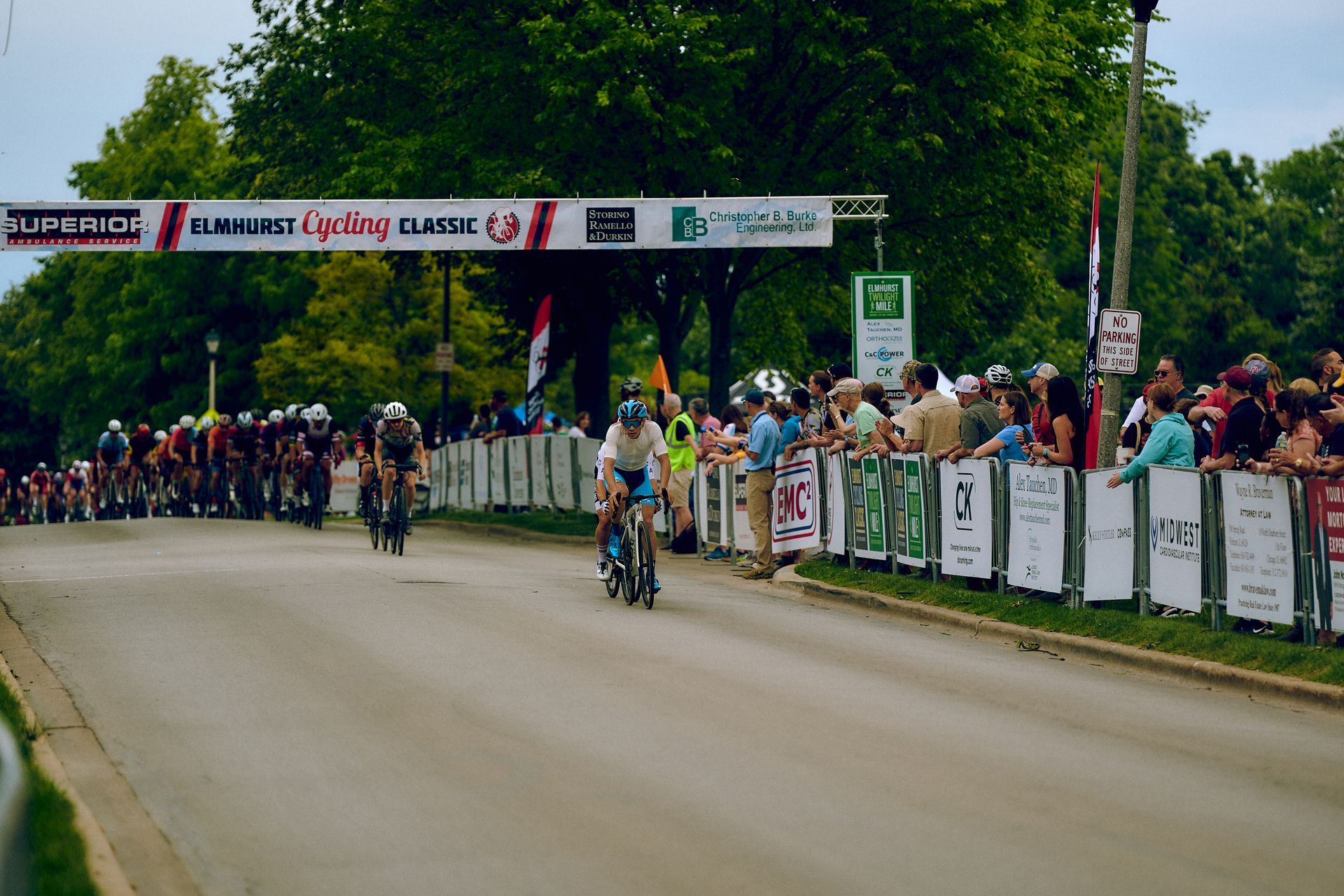 A group of people riding bicycles down a road with a sign that says ' lube ends ' on it