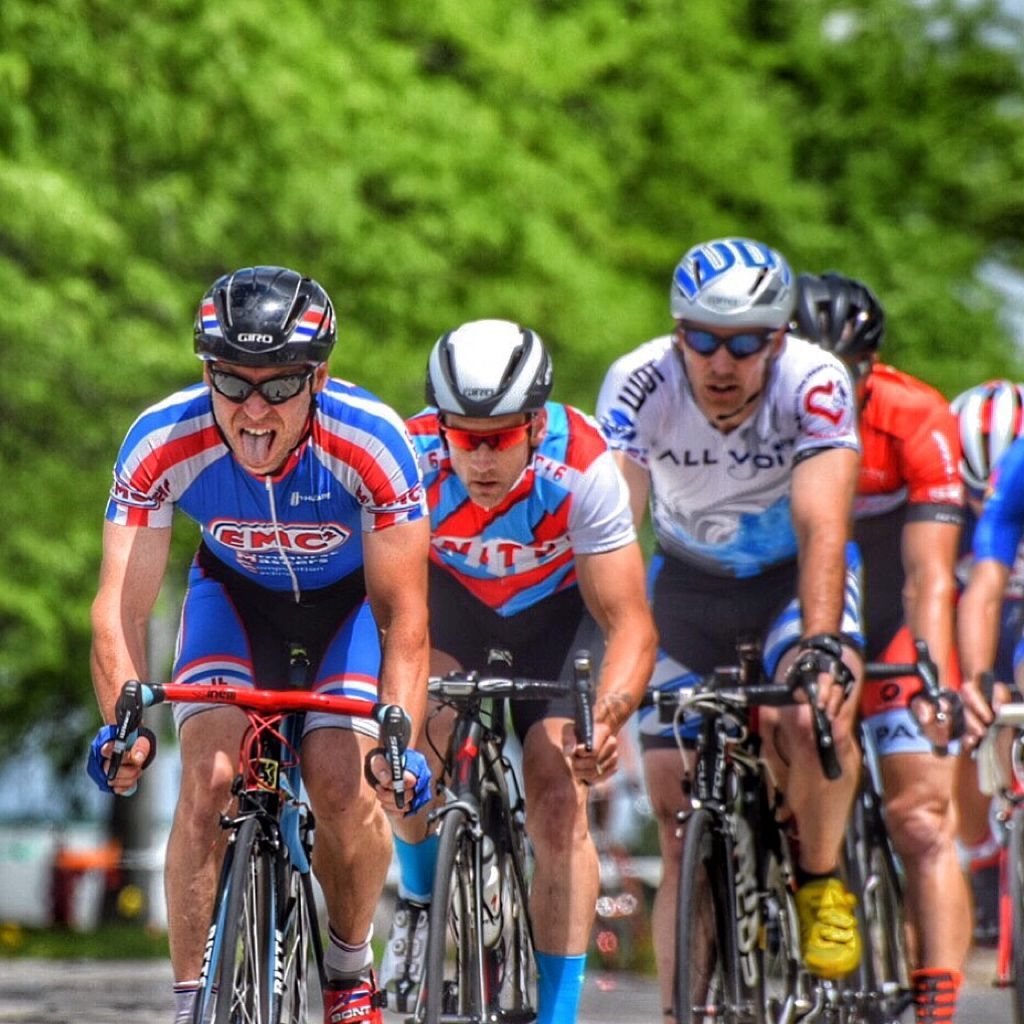 A group of cyclists are riding down a road and one of them is wearing a jersey that says epic
