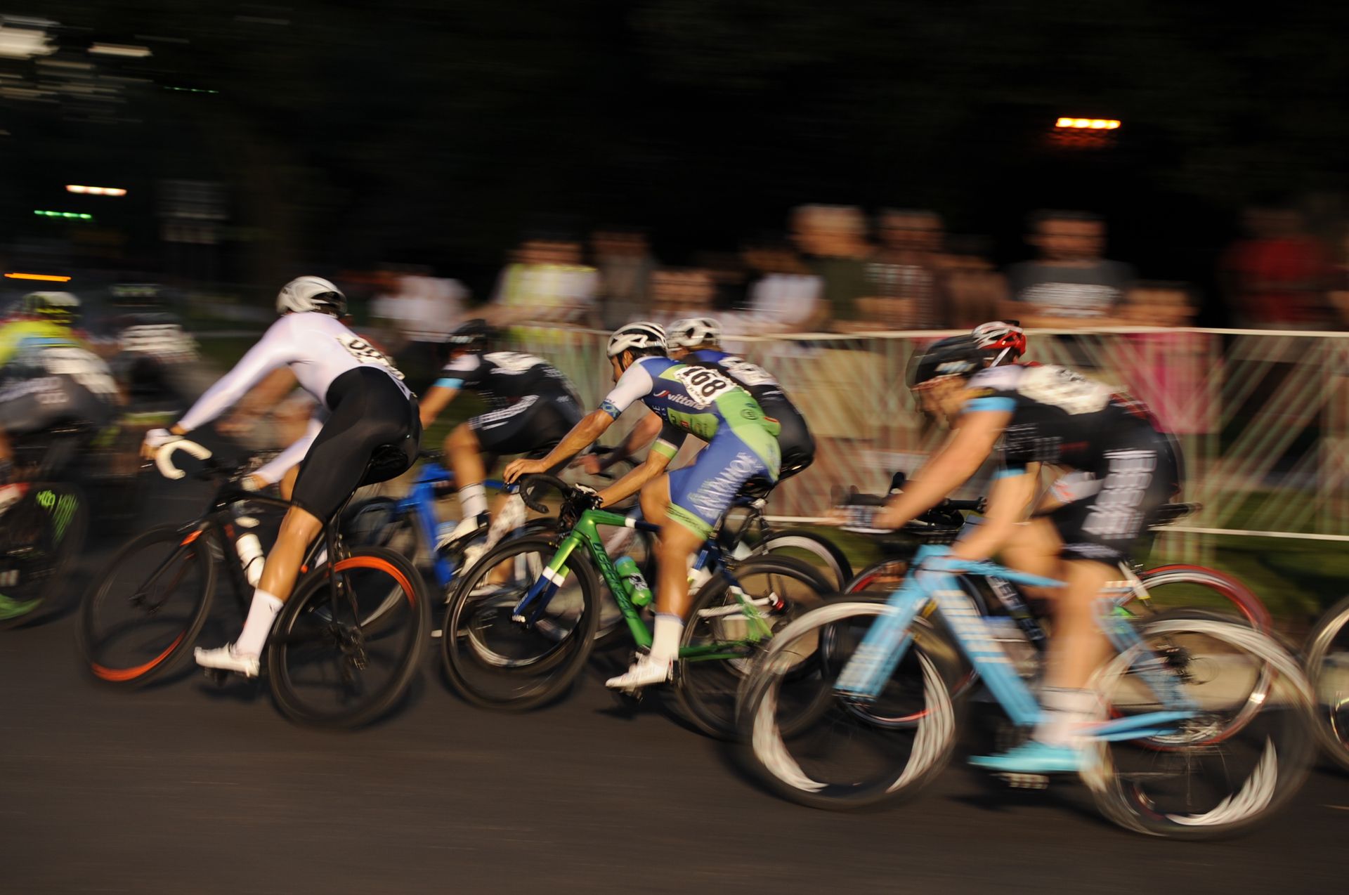 A group of cyclists are racing down a street at night