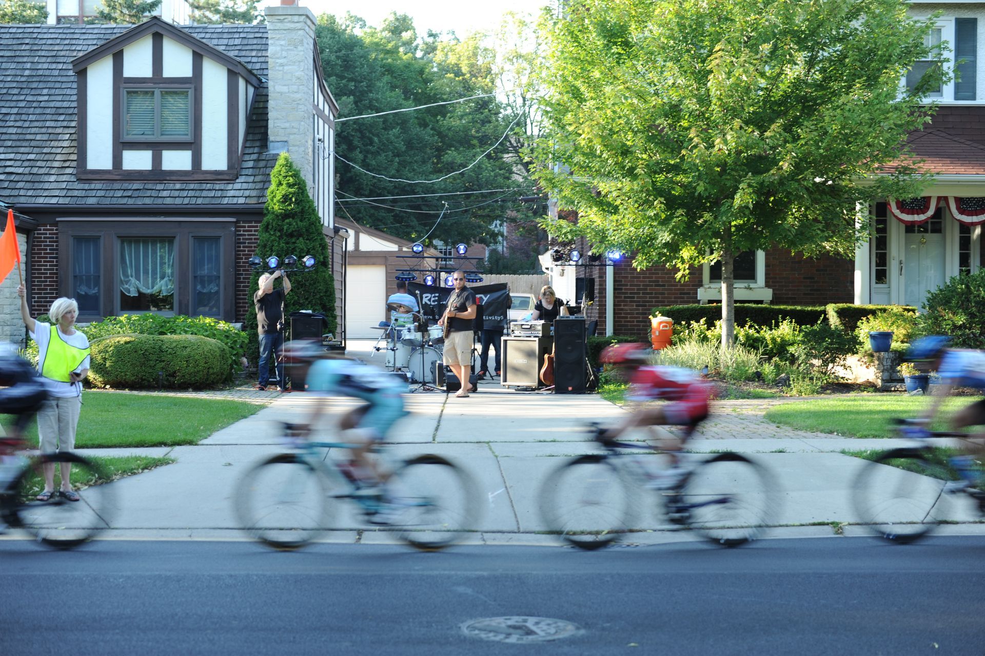 A group of cyclists are riding down a street in front of a house