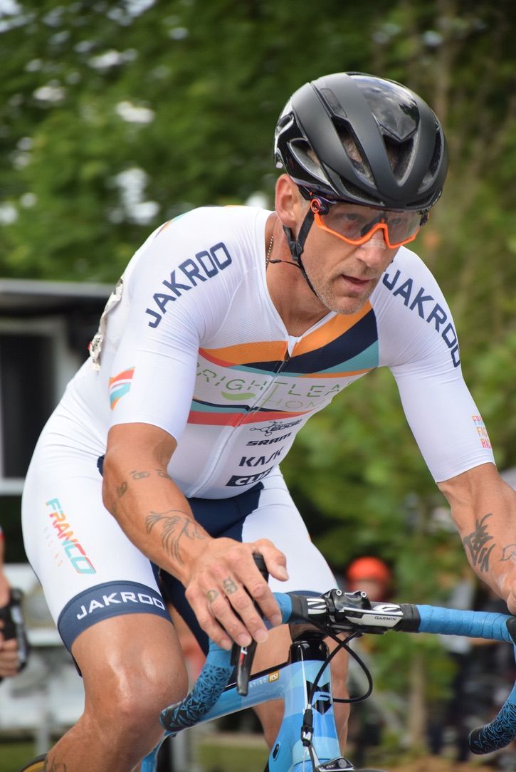 A man wearing a helmet and sunglasses is riding a bike.