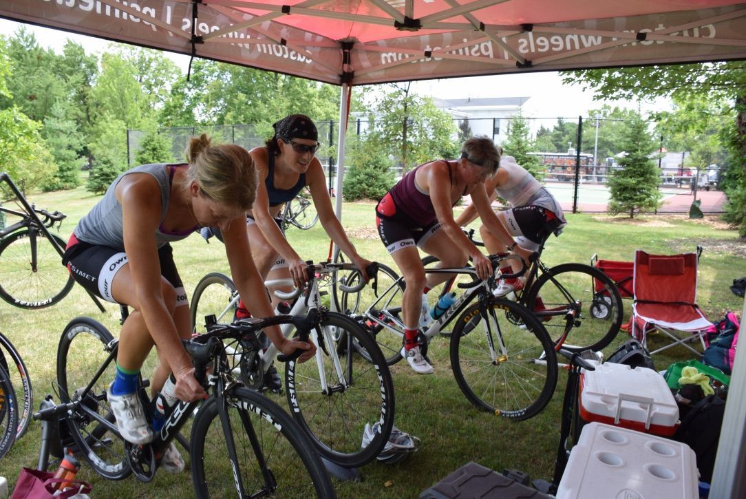 A group of women are riding bicycles under a tent.