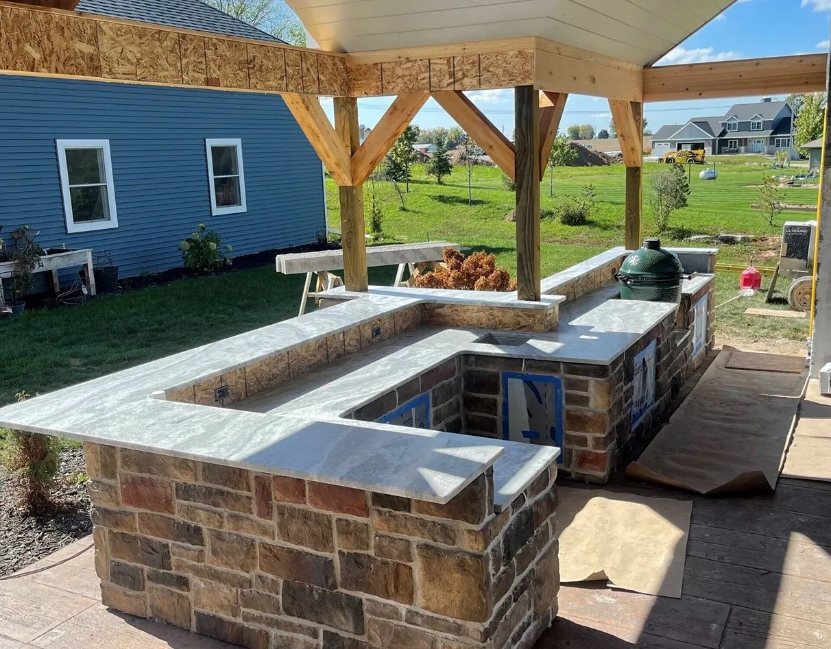 Outdoor kitchen with stone brick and granite countertops, under construction.