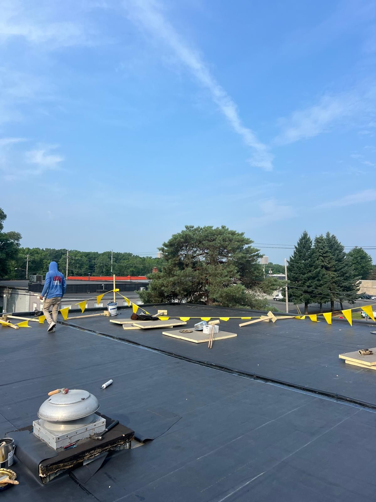 A man is walking on a flat roof with epdm material.