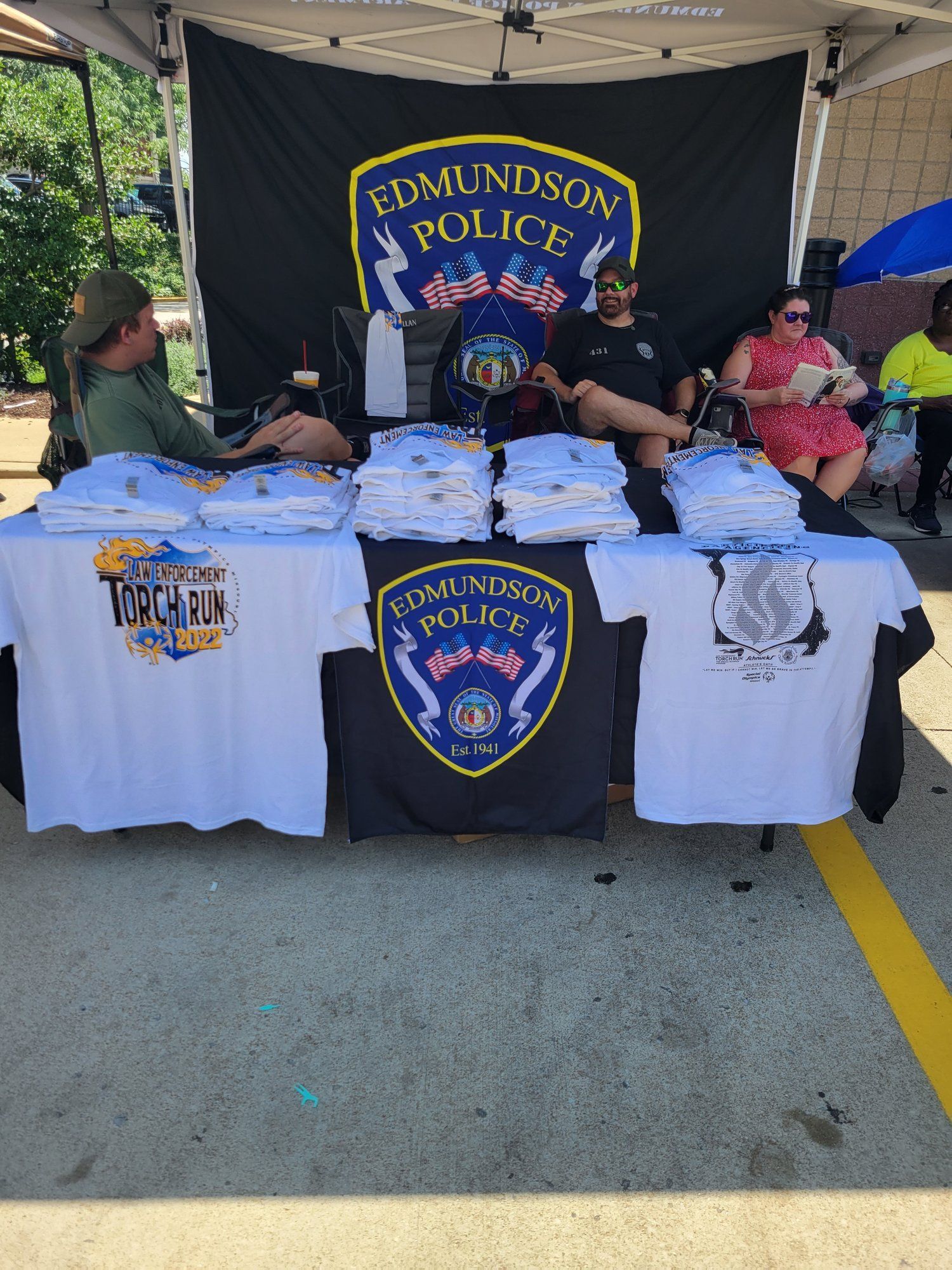 A group of people are sitting at a table with t-shirts on it.