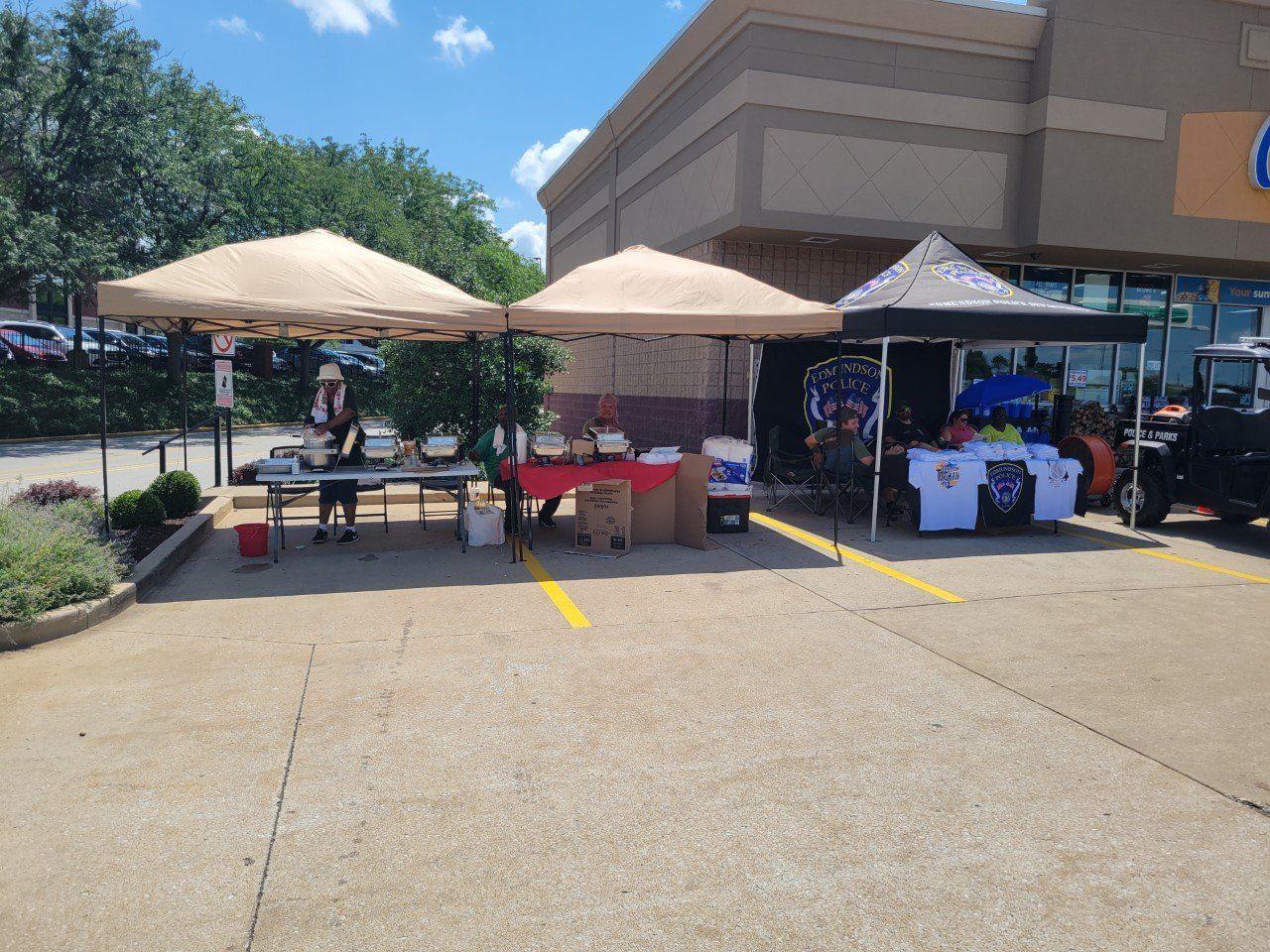 A parking lot with tents and tables in front of a store.