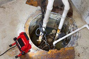 A red light is sitting next to a sump pump in a basement.
