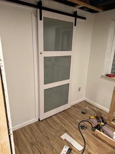 A sliding barn door is being installed in a room.