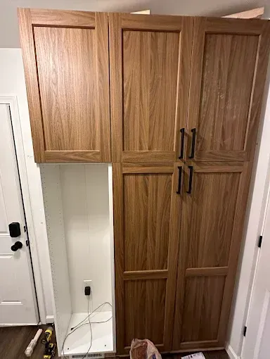 A wooden cabinet is being built in a room next to a door.