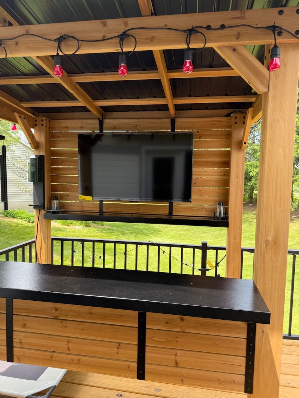 A wooden gazebo with a tv mounted on the wall
