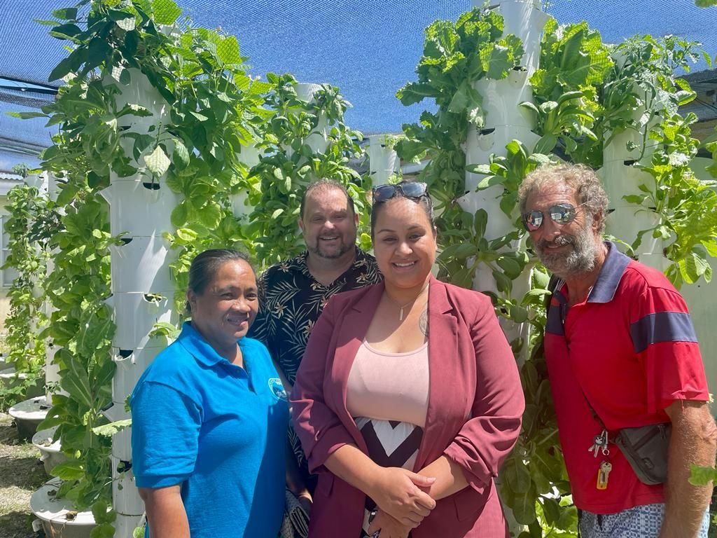 A group of people are posing for a picture in front of a hydroponic garden.