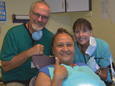 A woman in a dental chair is giving a thumbs up