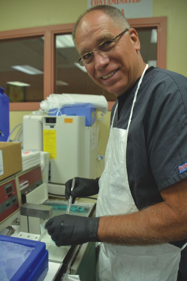 A man wearing an apron and gloves is working in a lab