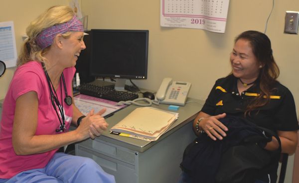 Two women are sitting at a desk and talking to each other