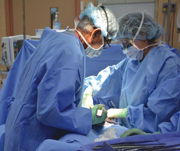 A man and a woman are operating on a patient in an operating room