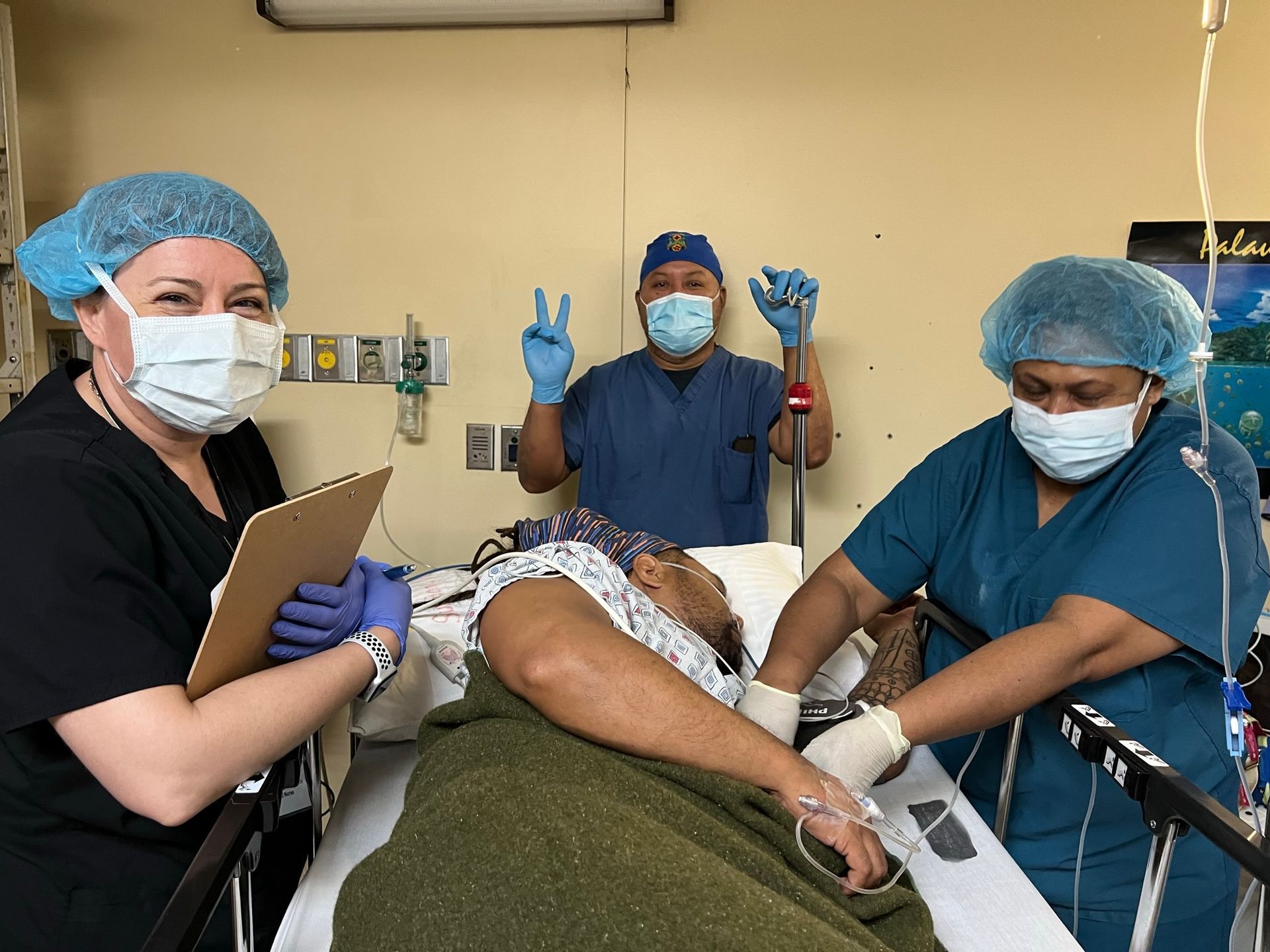 A man is laying in a hospital bed with two nurses standing around him