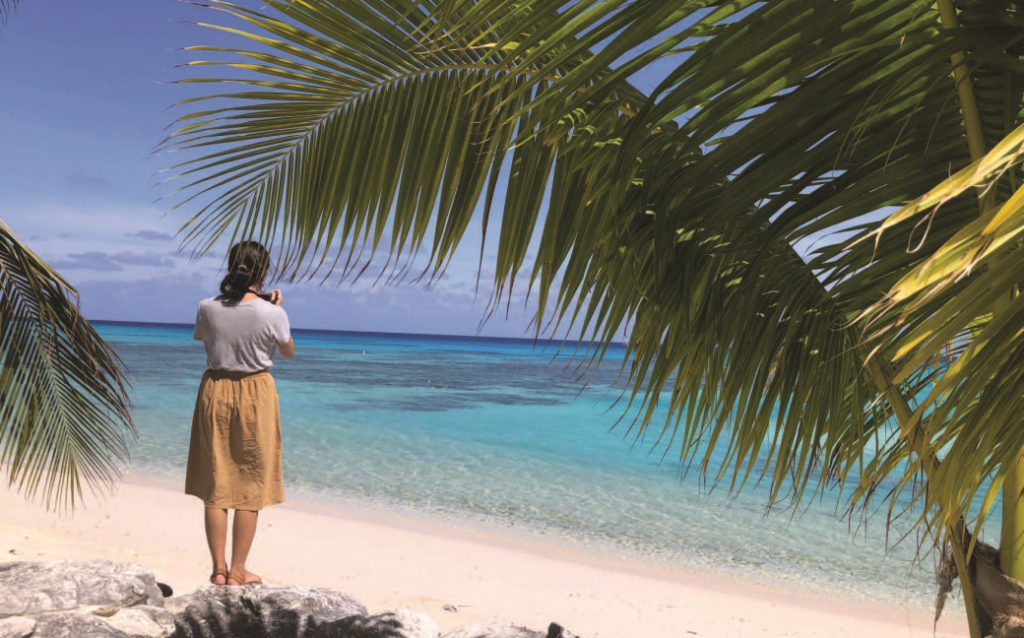 A woman is standing on a beach looking at the ocean.