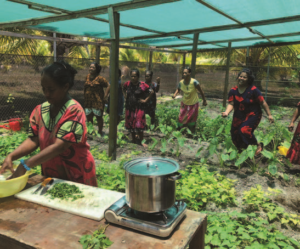 A woman is preparing food in a greenhouse with other people.