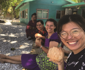 A woman is holding a coconut in front of a group of people