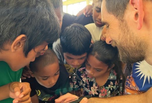 A group of children are looking at a cell phone.