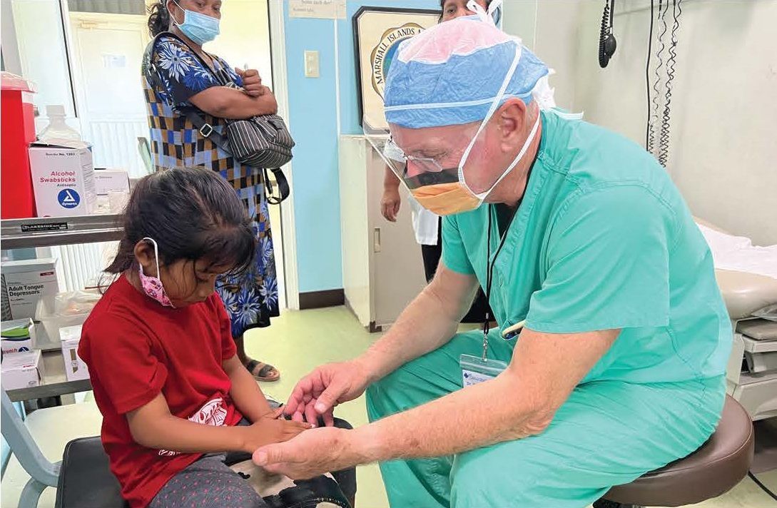 A surgeon is examining a little girl 's hand in an operating room.