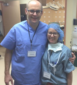 A man and a woman are posing for a picture in an operating room